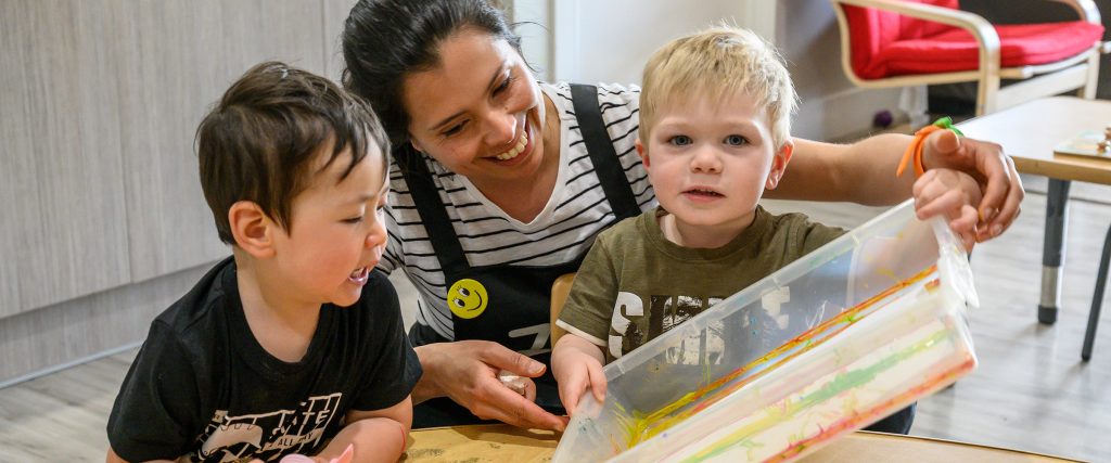 Childcare instructor teaching two children how to play