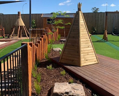 Child care play yard with teepee, cubby, deck and swings at Story House Early Learning Doreen.