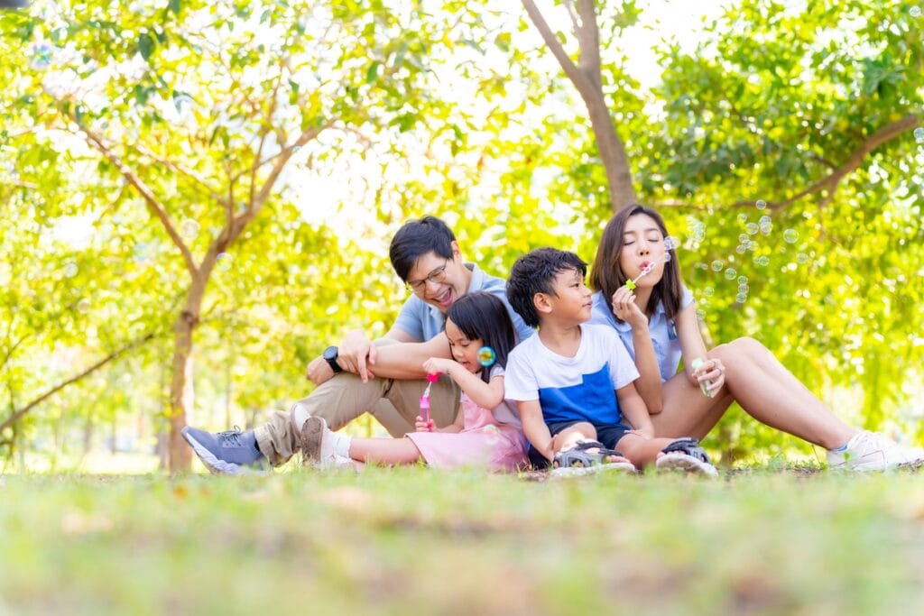 family playing with bubbles at the park