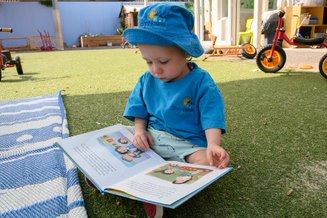 Language development in early childhood - child reading a book outside