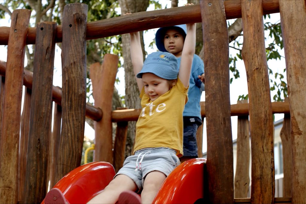 Child ready to go down a slide while another child behind waits