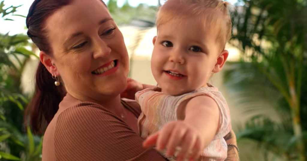 baby reaching for camera being held by parent